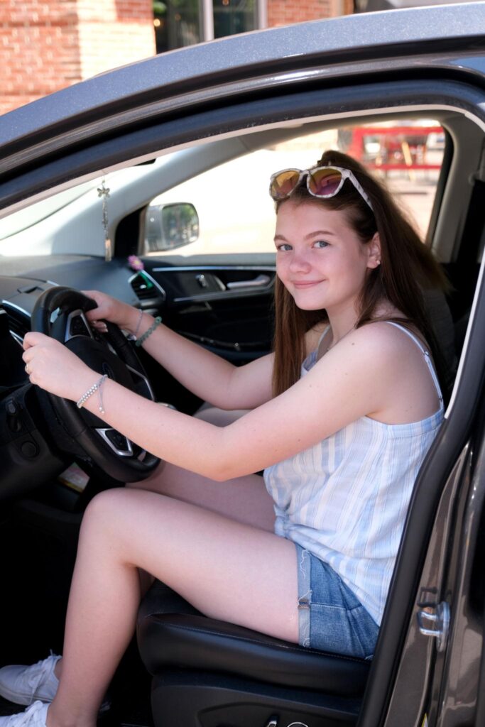 photo of a teenage girl behind the wheel of a car