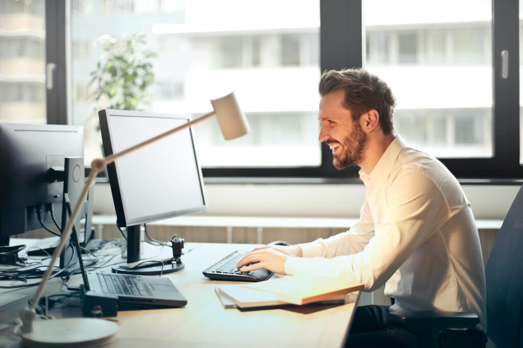 Photo by Andrea Piacquadio: https://www.pexels.com/photo/man-in-white-dress-shirt-sitting-on-black-rolling-chair-while-facing-black-computer-set-and-smiling-840996/